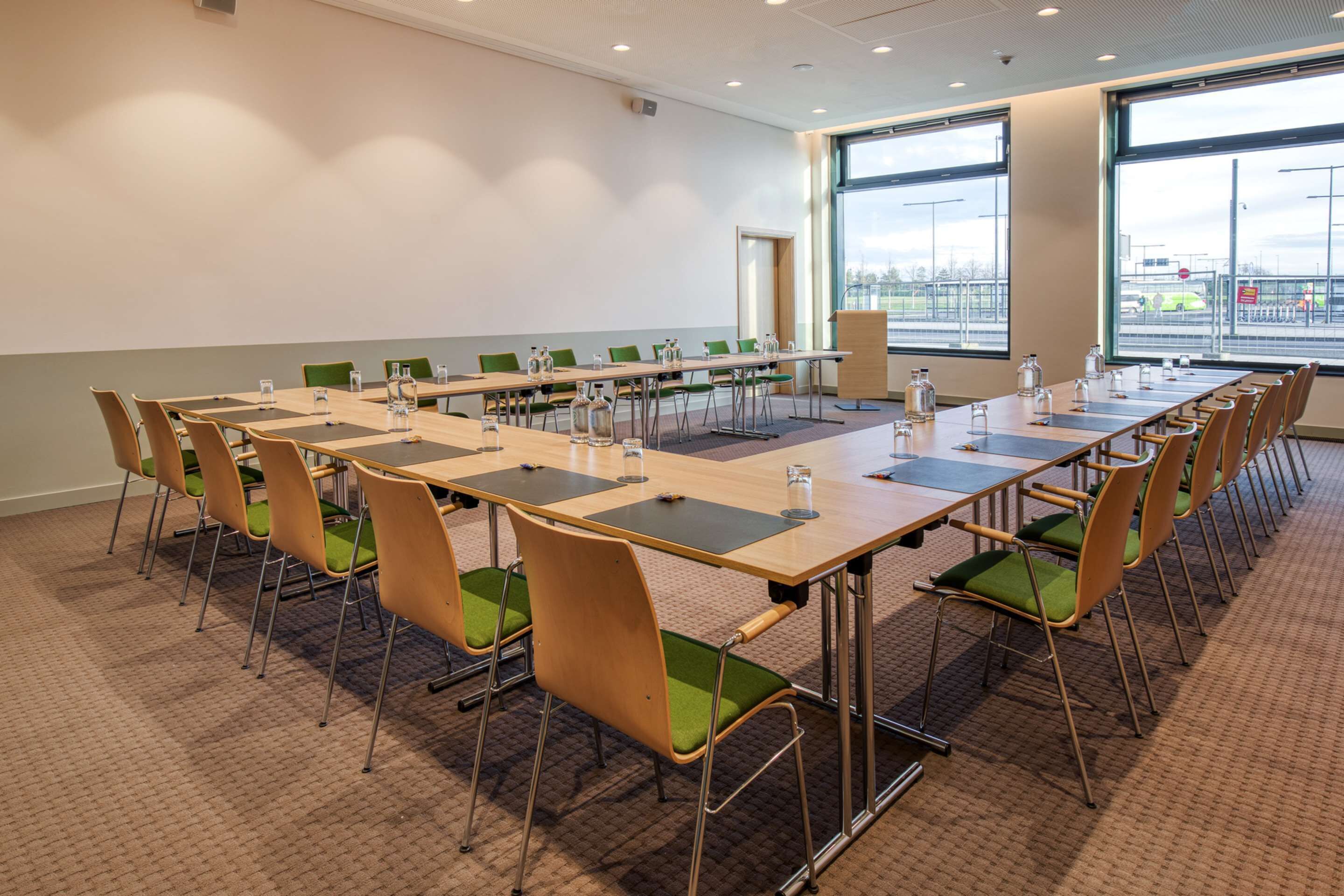 A conference room with a long table, green chairs, and large windows.