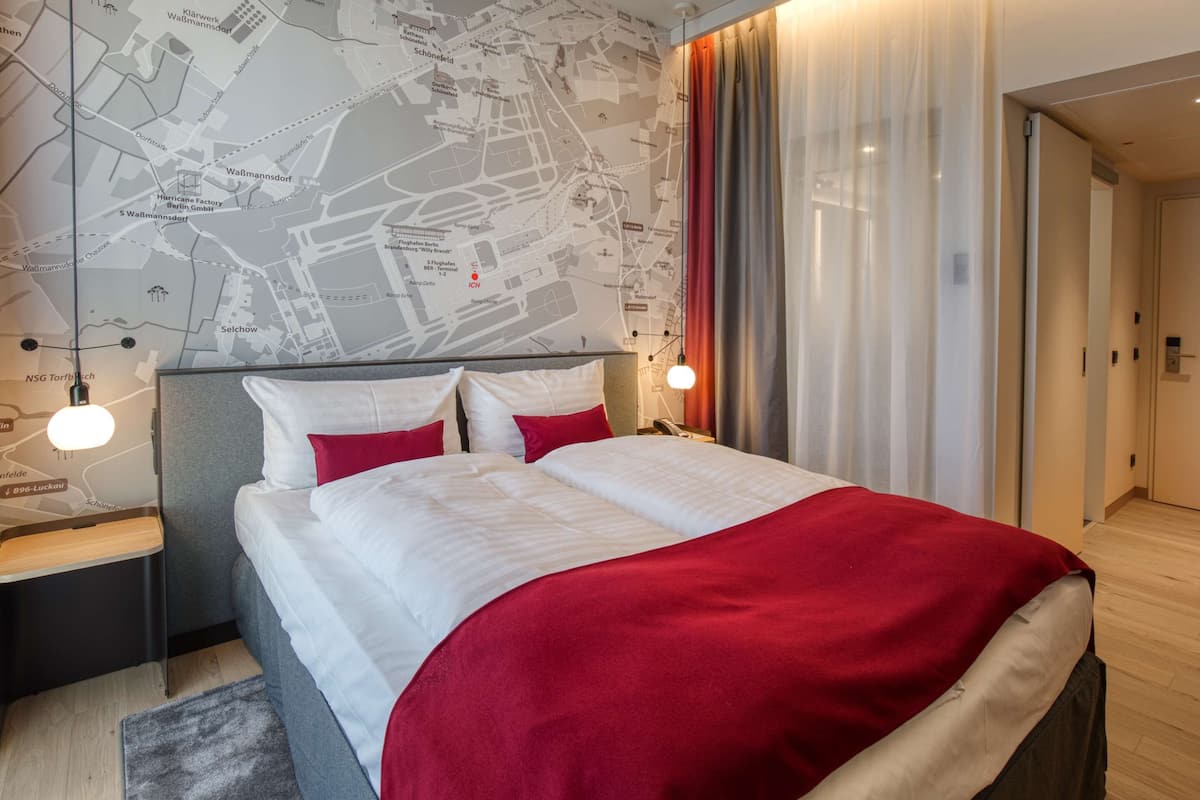Habitación de hotel con una cama grande, un mapa en la pared y un diseño moderno.