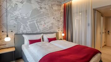 A hotel room with a large bed, a map on the wall, and a modern design.