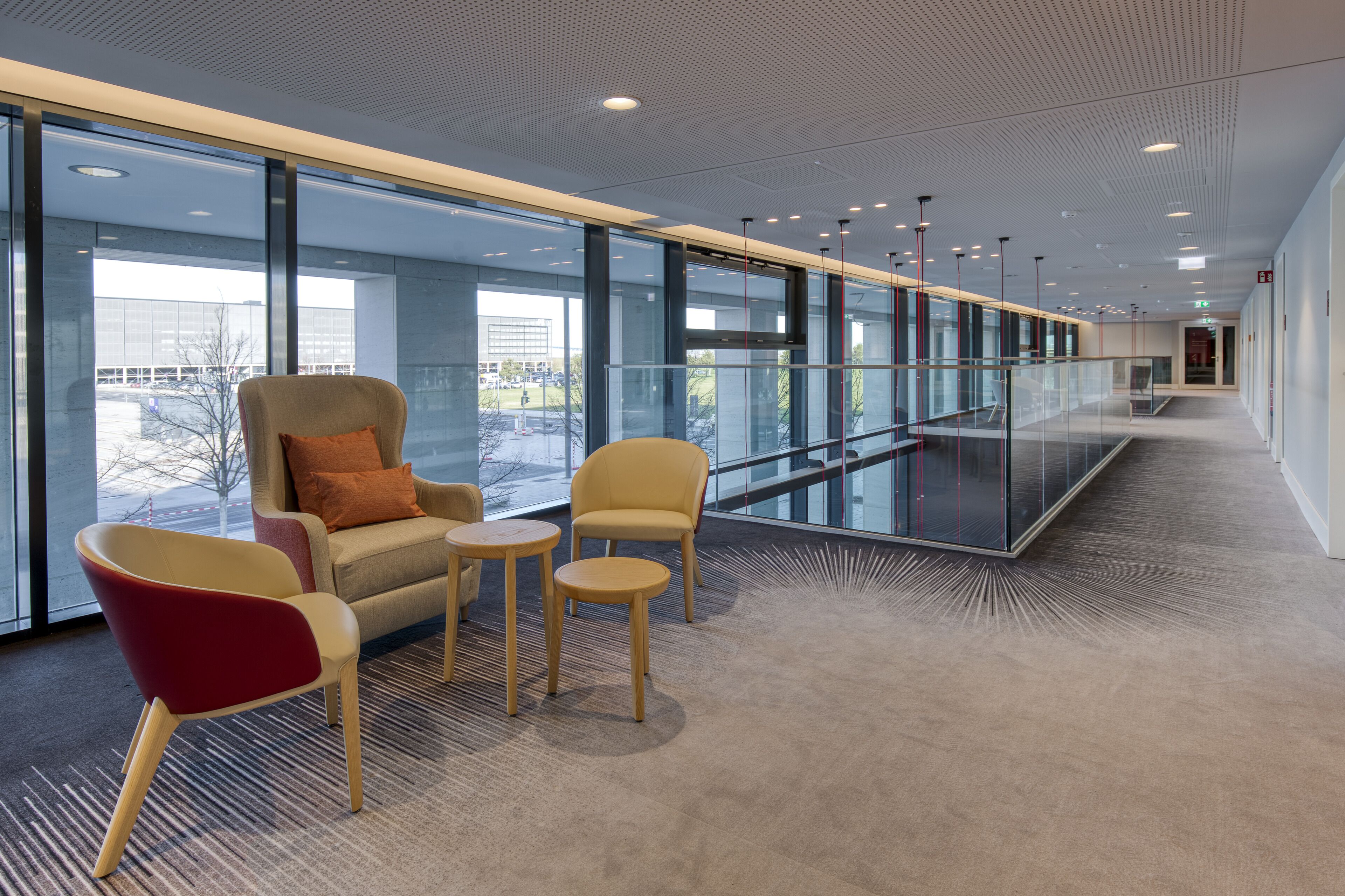 A modern interior with a glass railing, seating area, and a view of the outside.
