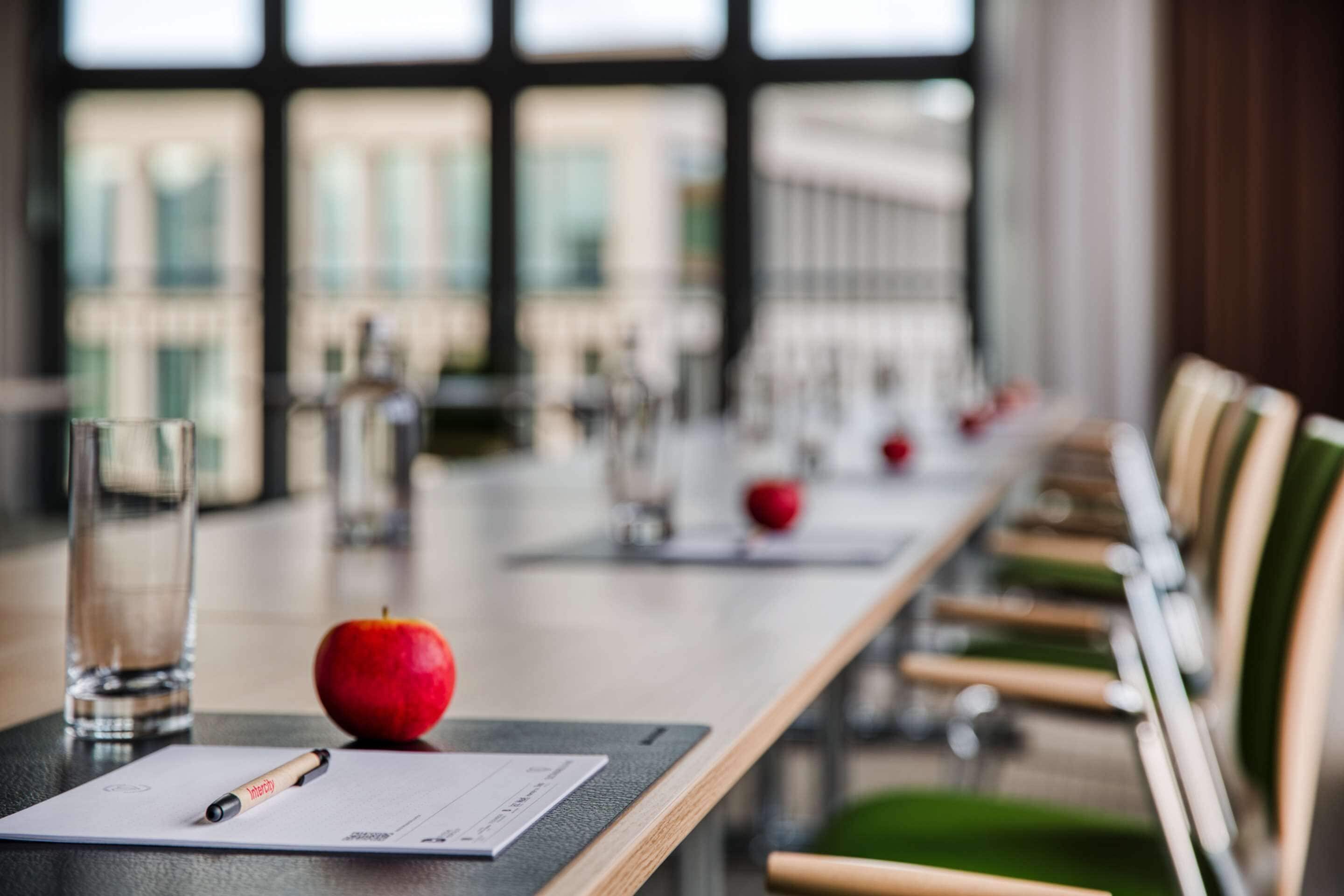 Una mesa de conferencias con un documento, un bolígrafo y una manzana.