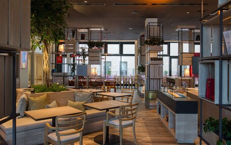 A modern interior with seating areas, tables, and shelves with plants.