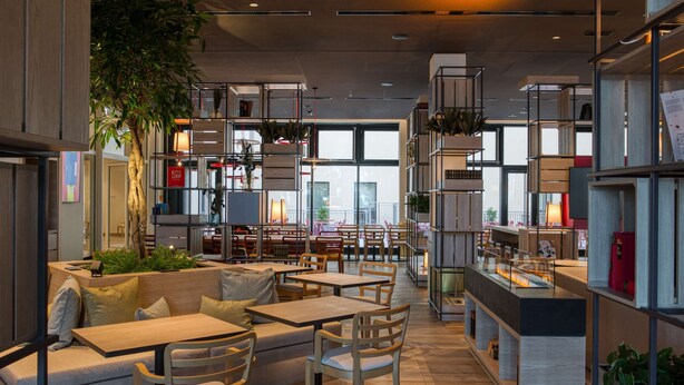 Een modern interieur met zithoeken, tafels en plantenbakken.