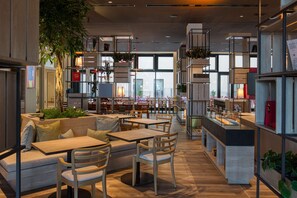 A modern interior with seating areas, tables, and shelves with plants. - IntercityHotel Berlin Airport BER Terminal 1+2  (Schoenefeld)
