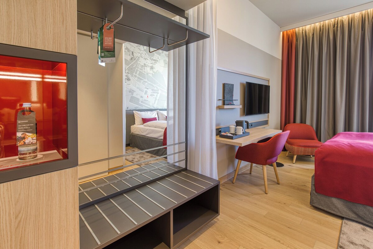 Een moderne hotelkamer met een bed, bureau en zithoek.