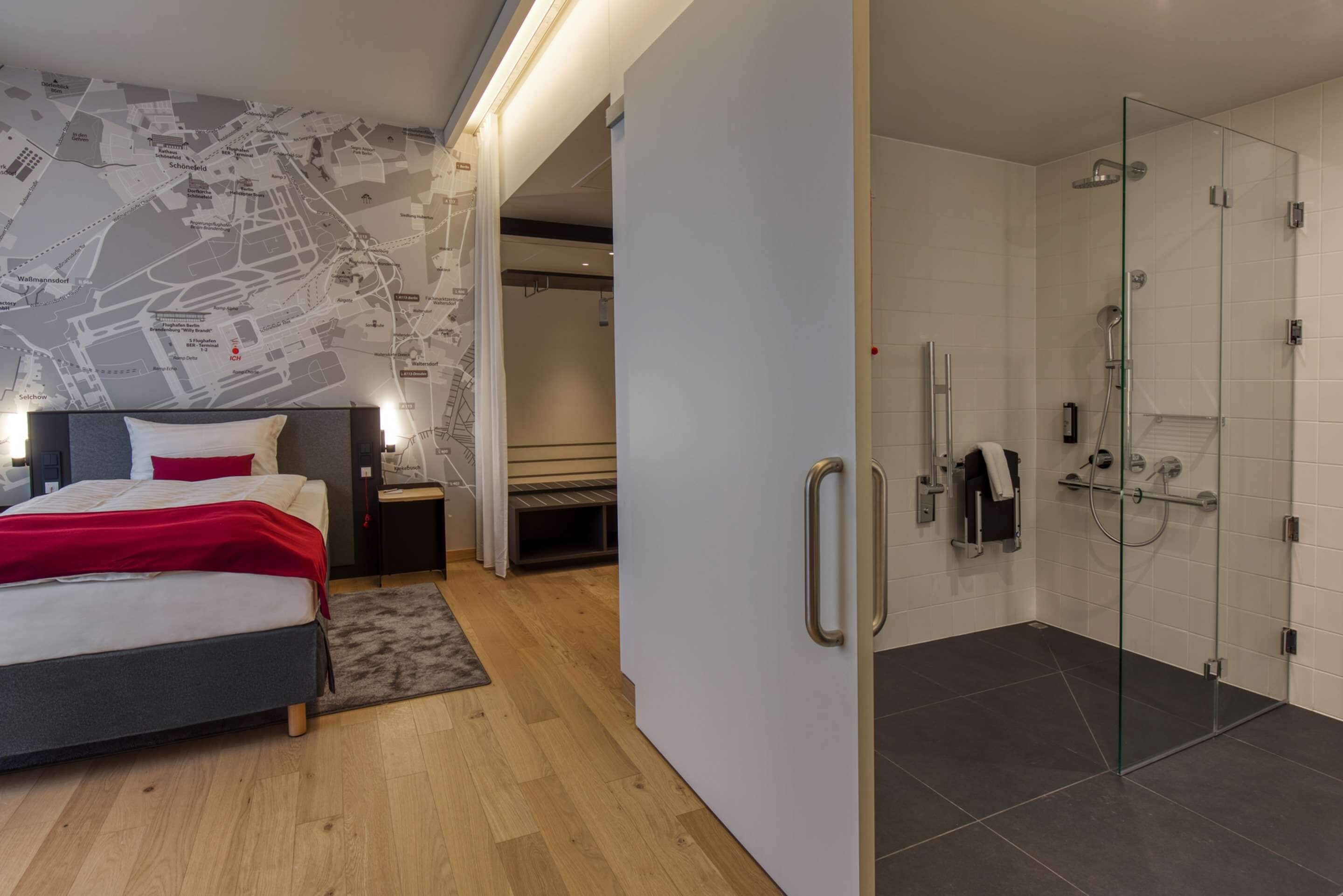 A modern hotel room with a bed, a map wall, a shower, and a small desk.