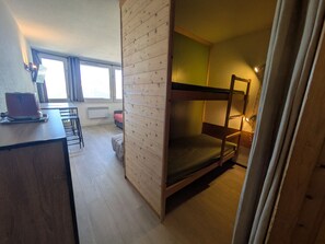 A compact room with bunk beds, a kitchenette, and a window with curtains. - Functional studio at the foot of the slopes, Mont Blanc view (Plagne Aime 2000)