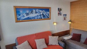 Ein gemütliches Zimmer mit einem roten Sofa, einem grauen Sofa und einem hölzernen Kopfteil.