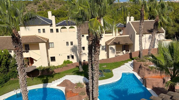 Un resort con piscina, palme e vista su una collina.