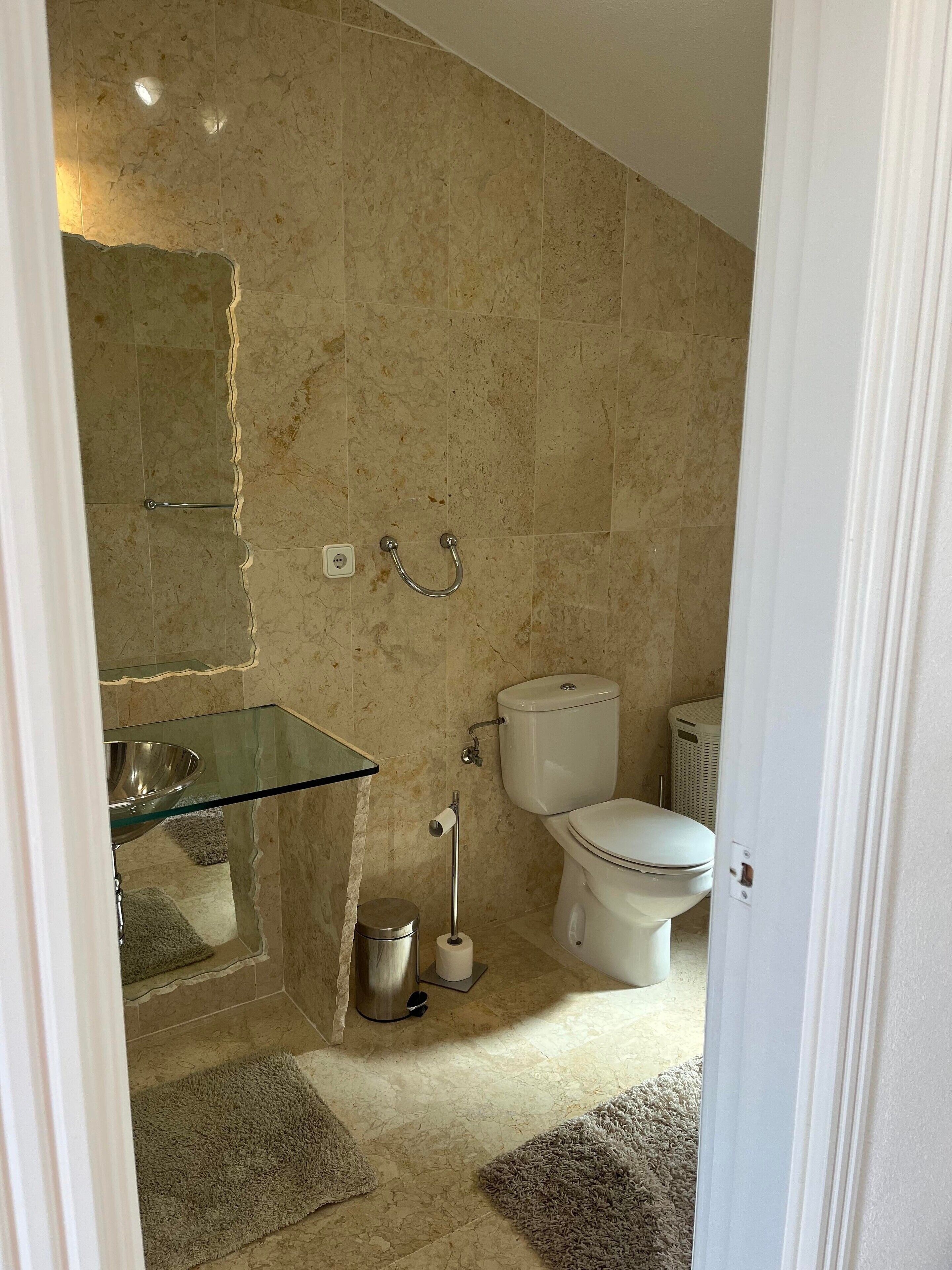 Ein Badezimmer mit einem Waschbecken aus Glas, einer Toilette und einem Bidet.