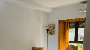 Una camera da letto con un letto, una sedia, una lampada da terra e una finestra con tende.