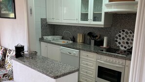 Una cucina con mobili bianchi, un piano di lavoro in granito, forno integrato e un'area pranzo con un tavolo e sedie.