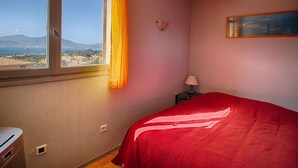 A bedroom with a bed, a window with a view of a landscape, a lamp, and a painting on the wall. - Charming Villa w/ Pool, Tennis, A/C, Near Beach in Porticcio - Sleeps 6 (Porticcio)