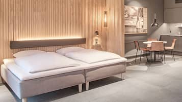 Un dormitorio moderno con cama, mesitas de noche, un escritorio y sillas.