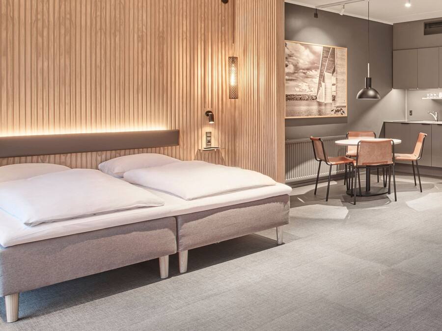 Un dormitorio moderno con cama, mesitas de noche, un escritorio y sillas.