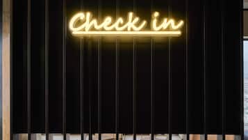 A neon sign with the text "Check in" against a dark background with vertical slats.