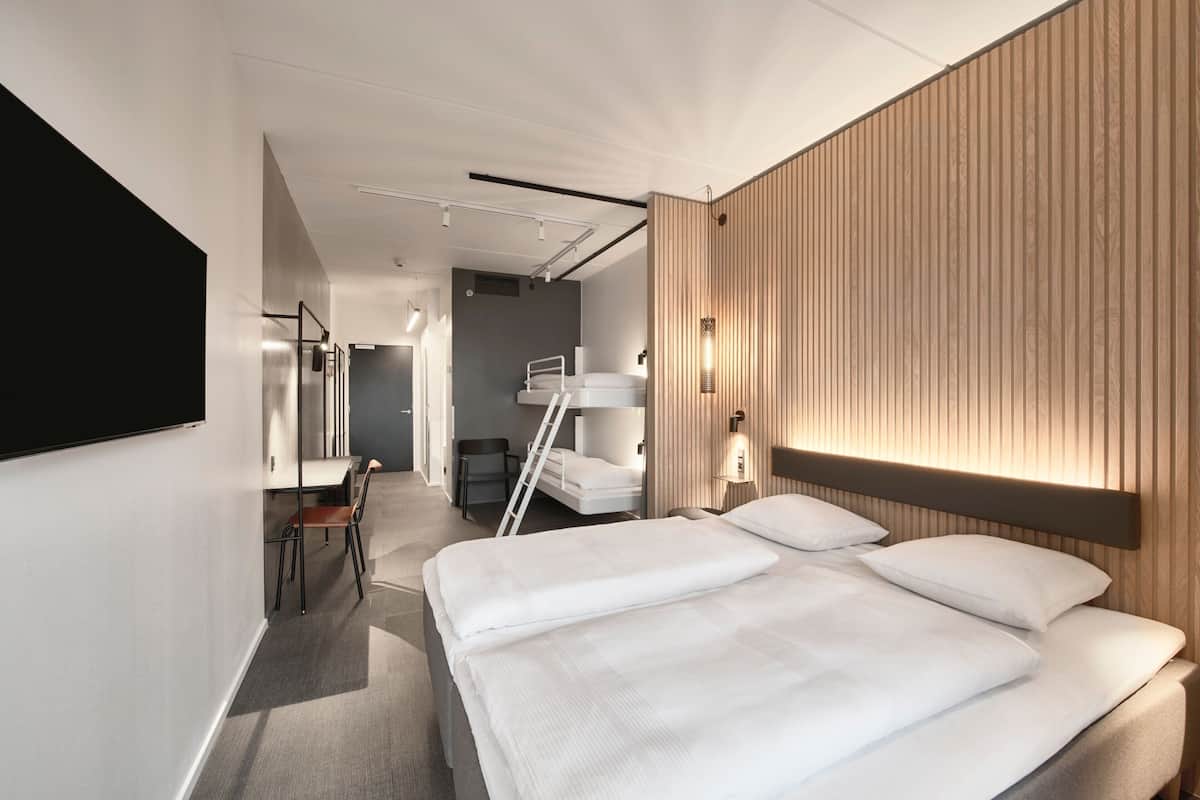 A modern hotel room with a large bed, a desk, and a chair.