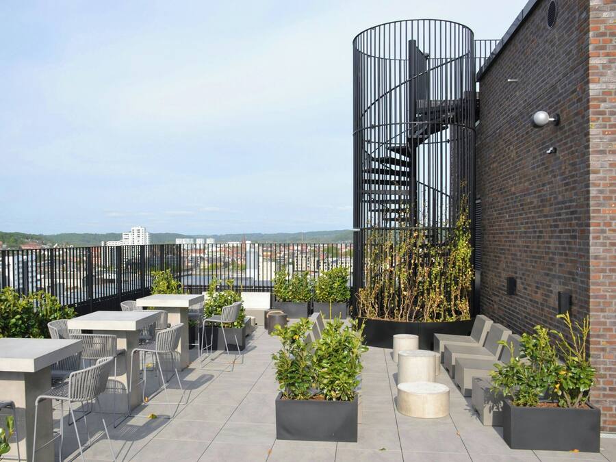 A rooftop terrace with outdoor seating, a spiral staircase, and a view of the city.