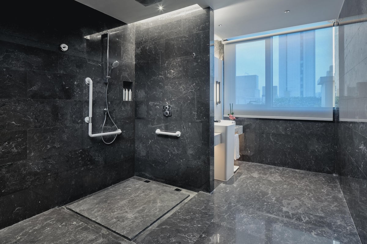Une salle de bain moderne avec une douche à l’italienne, des murs en marbre et une grande fenêtre.