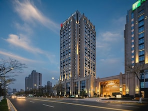 Un hôtel de grande hauteur, doté d’une façade moderne, de nombreux étages et d’une entrée imposante avec une façade en verre.