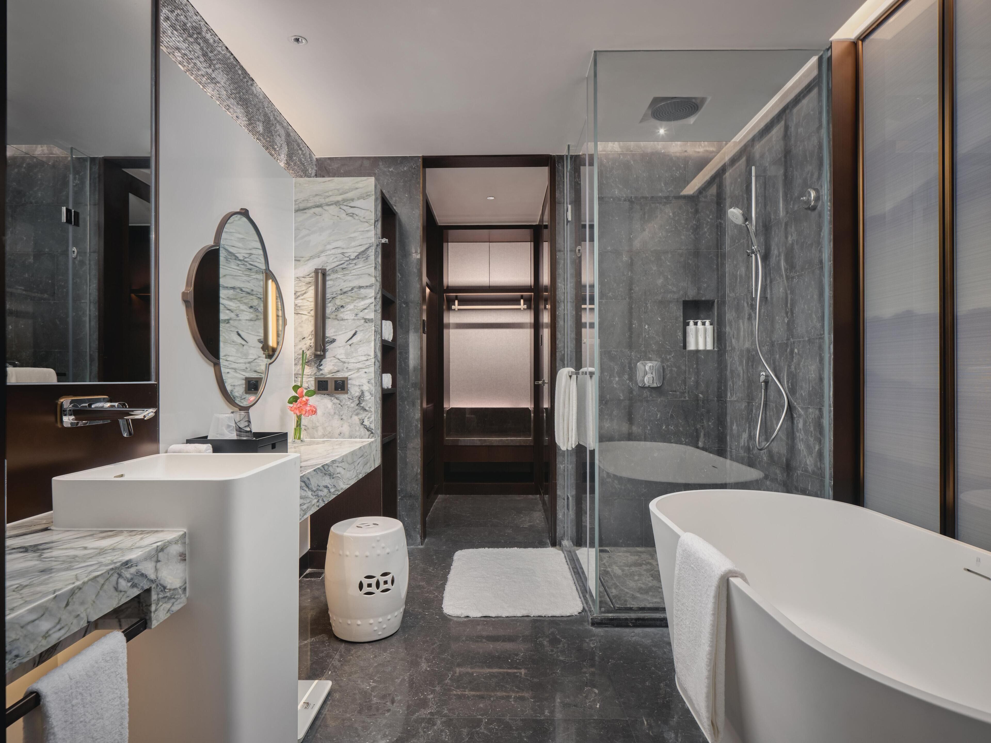 Un baño moderno con tocador de mármol, un espejo grande, cabina de ducha y bañera.