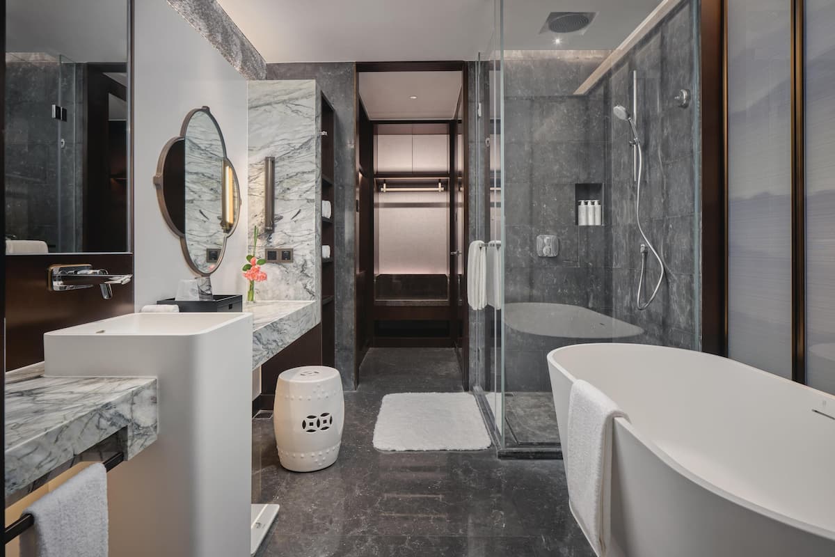 Une salle de bain moderne avec un meuble-lavabo en marbre, un grand miroir, une cabine de douche et une baignoire.