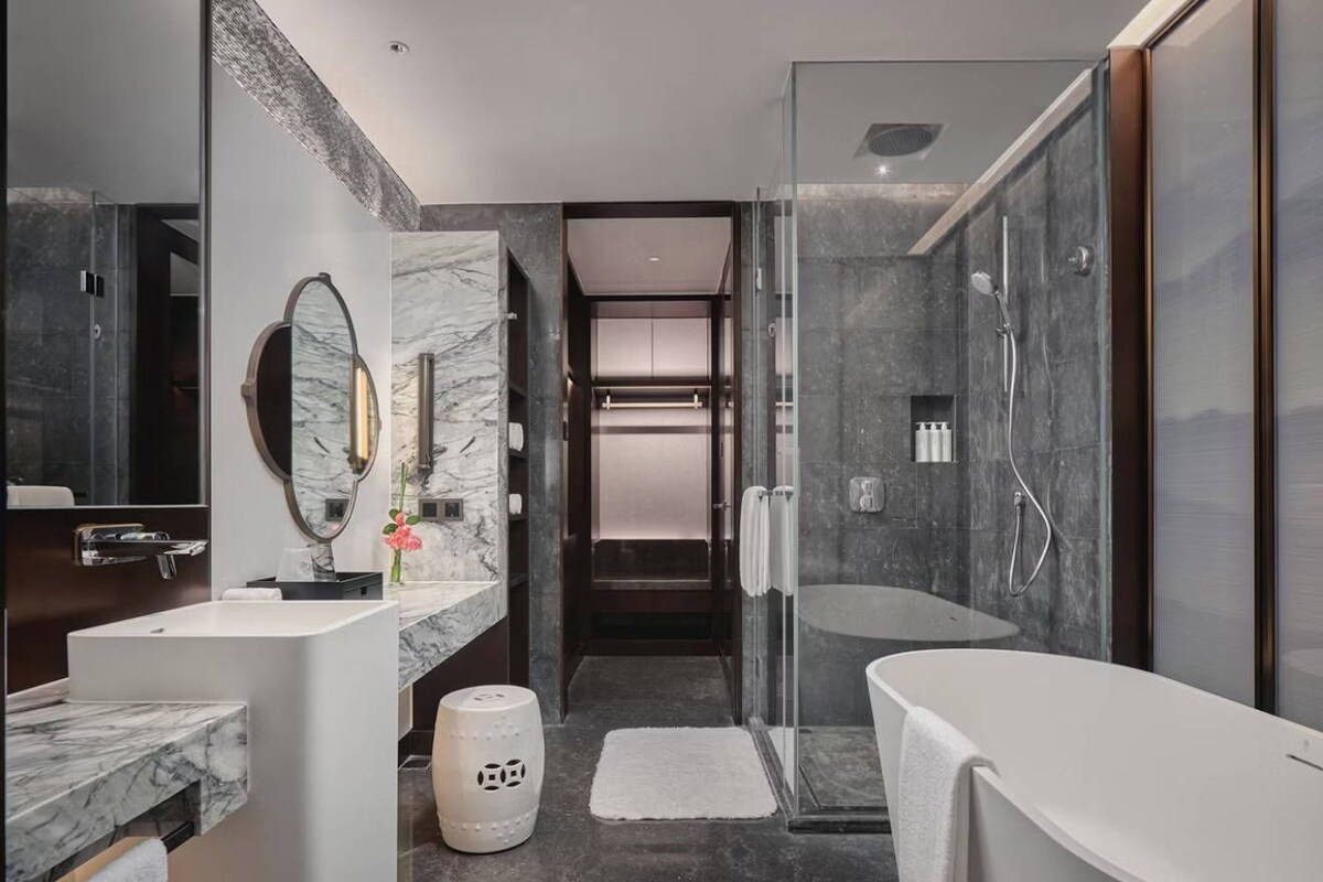 A modern bathroom with a glass-enclosed shower, a standalone bathtub, and a marble vanity.