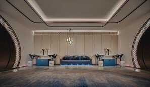 A modern hotel lobby with a sofa, two reception desks, a patterned ceiling, and a decorative wall panel. - Hualuxe Kunshan Huaqiao (Suzhou)