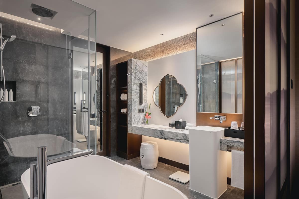 Une salle de bain moderne dotée d’une grande baignoire, d’une douche séparée, d’un meuble-lavabo avec miroir et d’un plan de toilette en marbre.