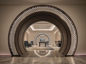 A modern hotel lobby with a central seating area, a patterned archway, and a reflective floor. - Hualuxe Kunshan Huaqiao (Suzhou)