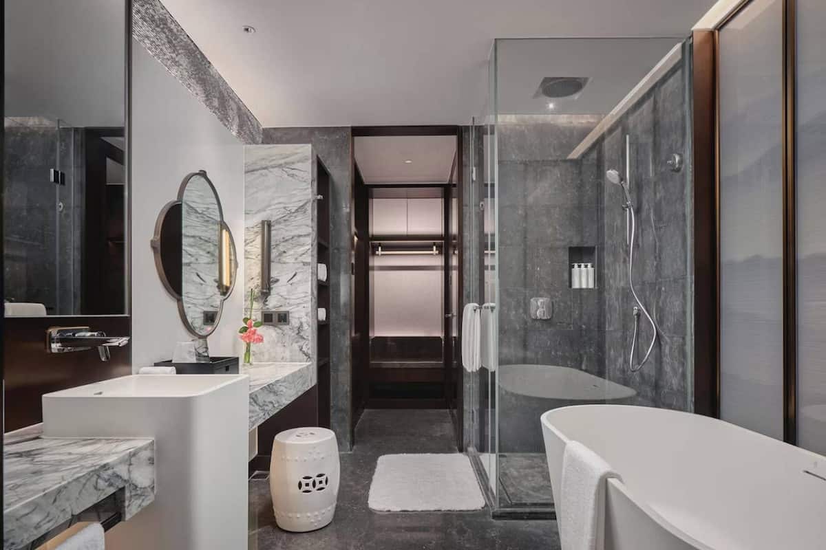 Une salle de bain moderne avec une douche à parois de verre, une baignoire sur pieds et un meuble-lavabo en marbre.