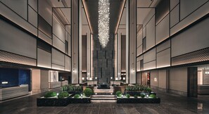 Un moderno vestíbulo de hotel con una fuente central, zonas de estar y una recepción.