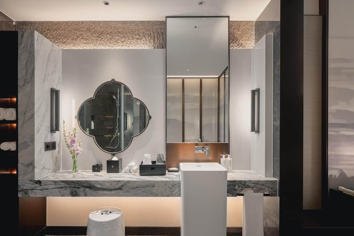 Une salle de bain moderne avec un meuble-lavabo en marbre, un grand miroir, un porte-serviettes et une balance.