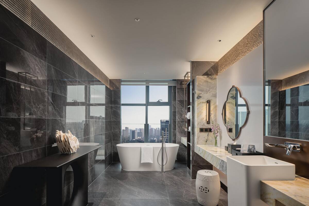 Une salle de bain moderne avec une grande baignoire, un meuble-lavabo avec un miroir et une vue sur la ville.