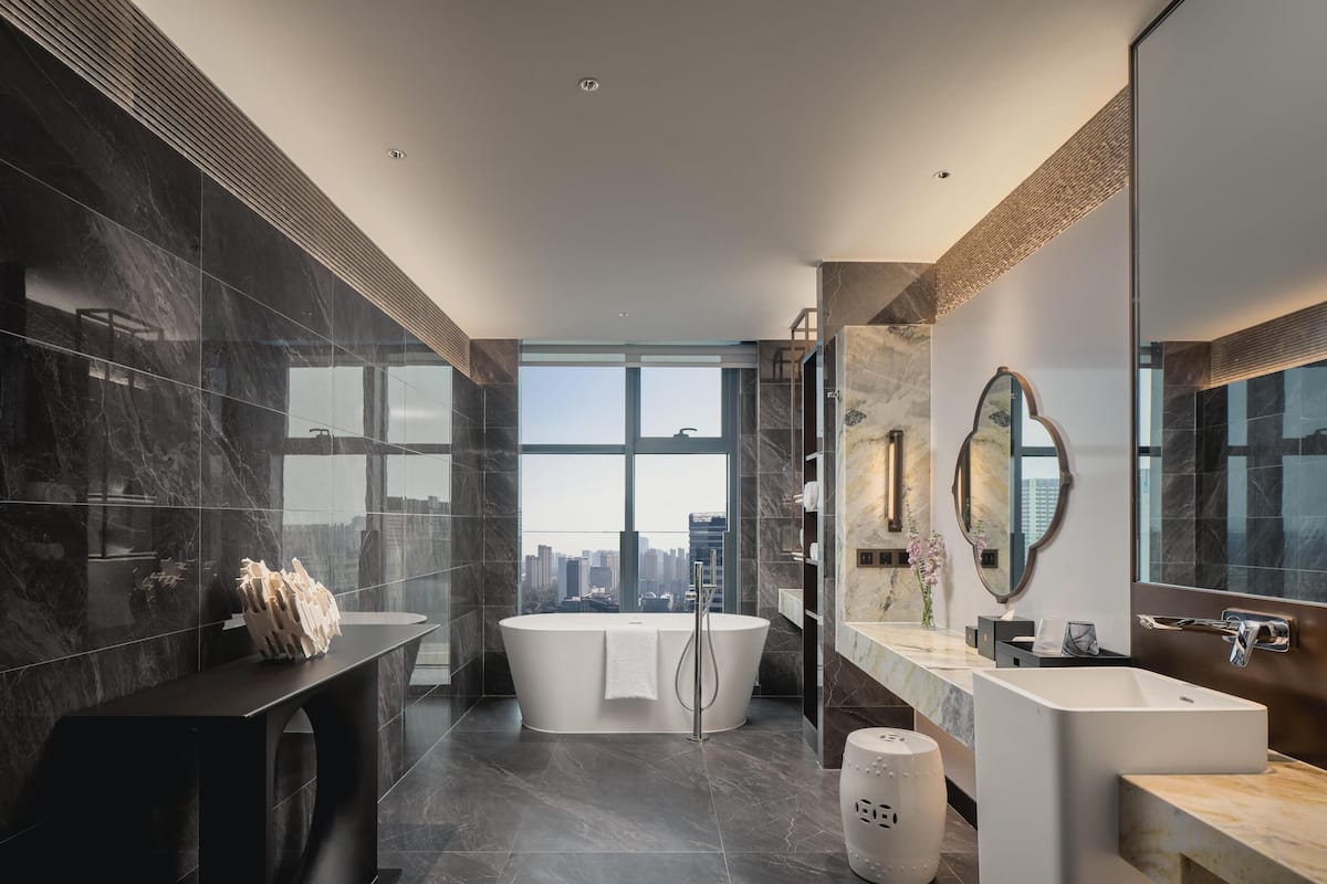 Un bagno moderno con una grande vasca, un mobile lavabo con specchio e vista sulla città.