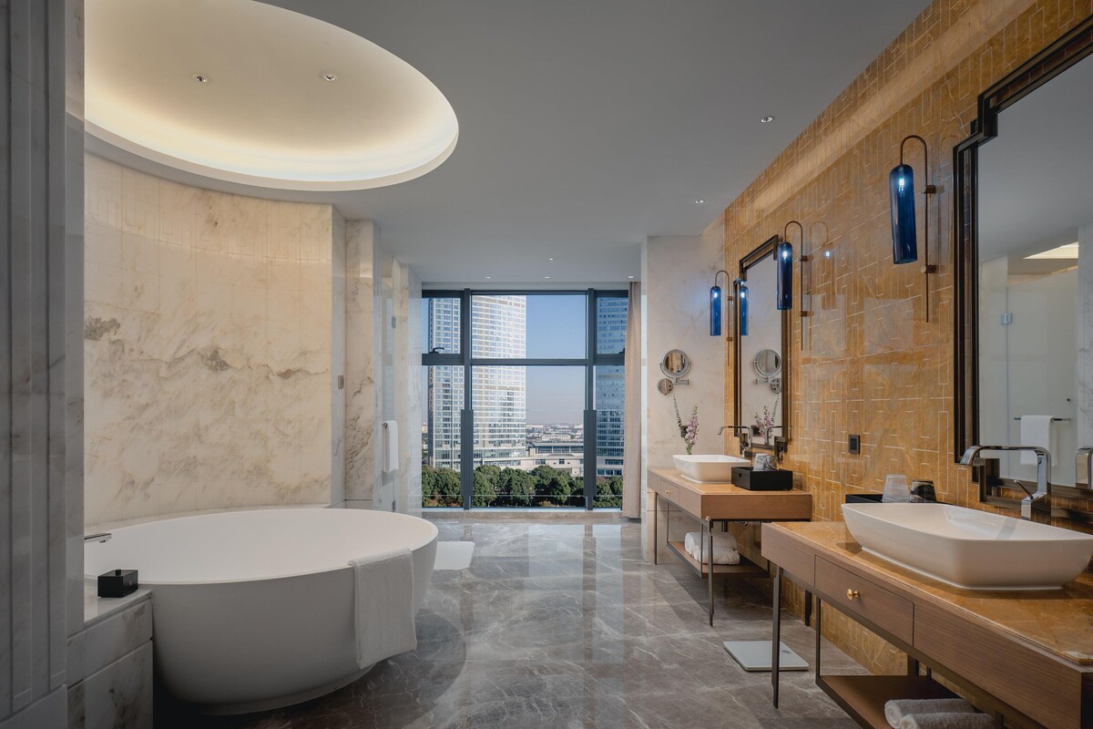 A modern bathroom with a large bathtub, two sinks, and a large mirror.