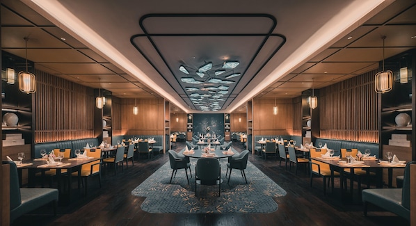 Un intérieur de restaurant moderne avec un espace de restauration central, des banquettes et un tapis à motifs.