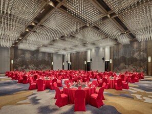 A large banquet hall with rows of round tables, red chairs, and a ceiling adorned with numerous lights. - Hualuxe Kunshan Huaqiao (Suzhou)