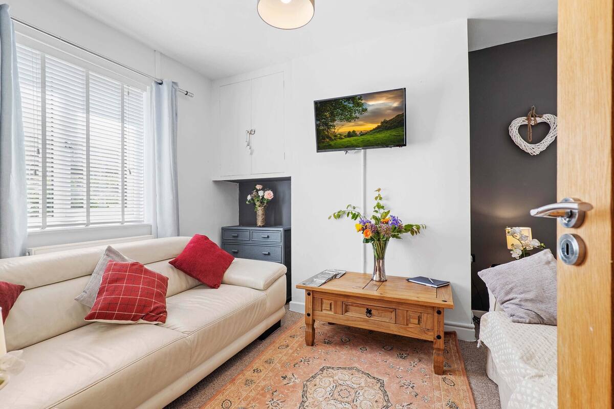 A modern living room with a beige sofa, a wooden coffee table, and a TV mounted on the wall.