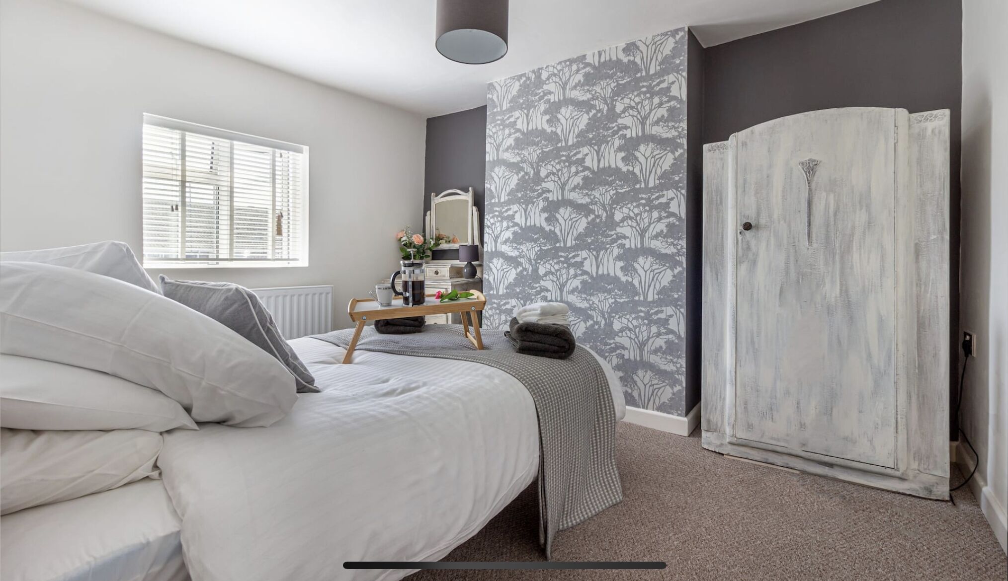 Een slaapkamer met een bed, nachtkastje, dressoir en een kledingkast.