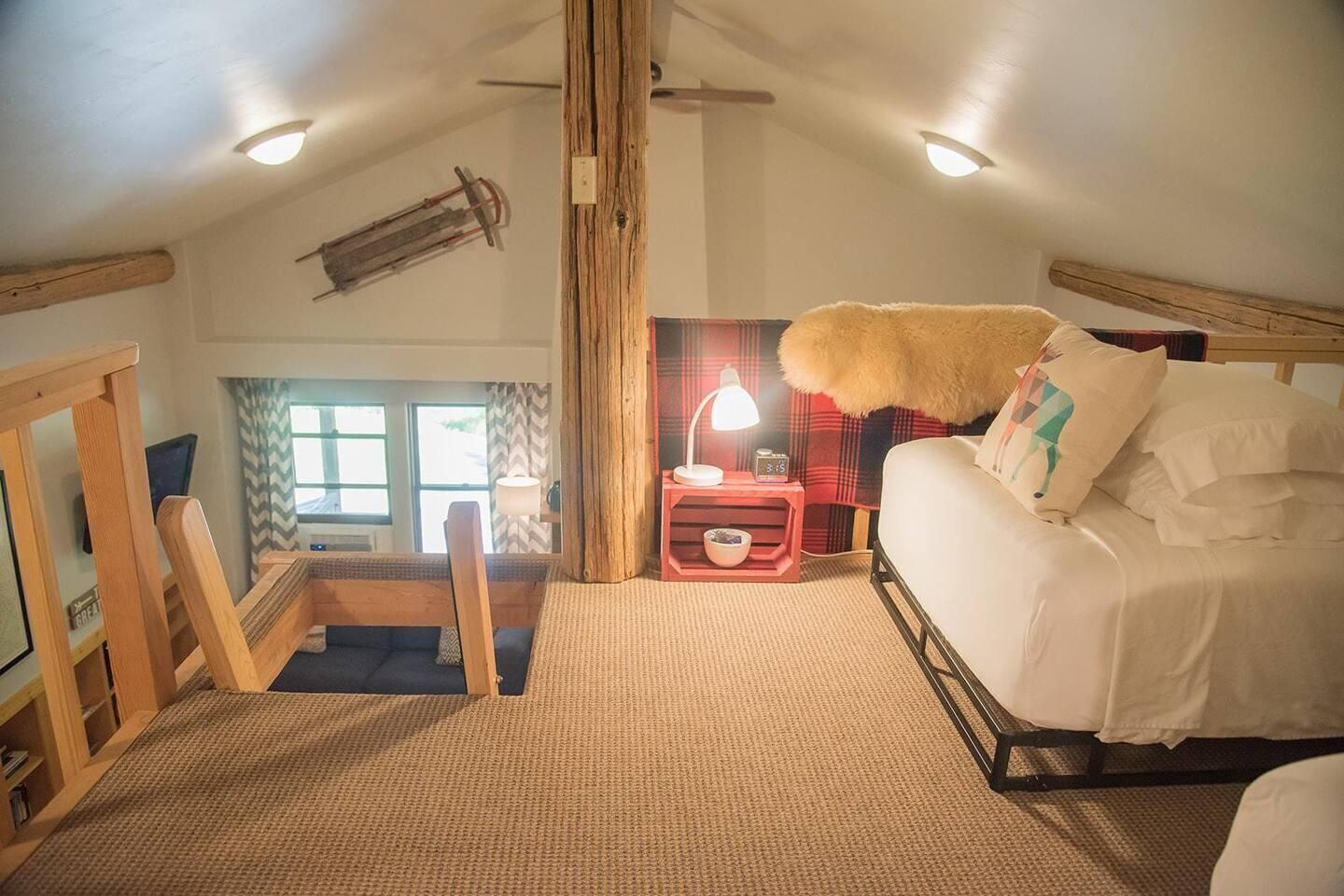 Un dormitorio con una cama, una mesita de noche, una lámpara y un ventanal.