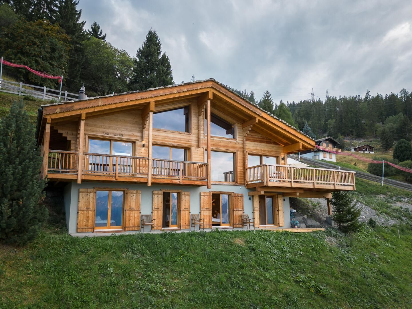 Eine zweigeschossige Holzhütte mit Balkonen, großen Fenstern und einem Steinfundament.