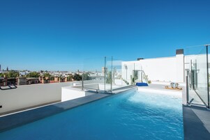 Una piscina en la azotea con agua cristalina, rodeada de arquitectura moderna y vistas de la ciudad.