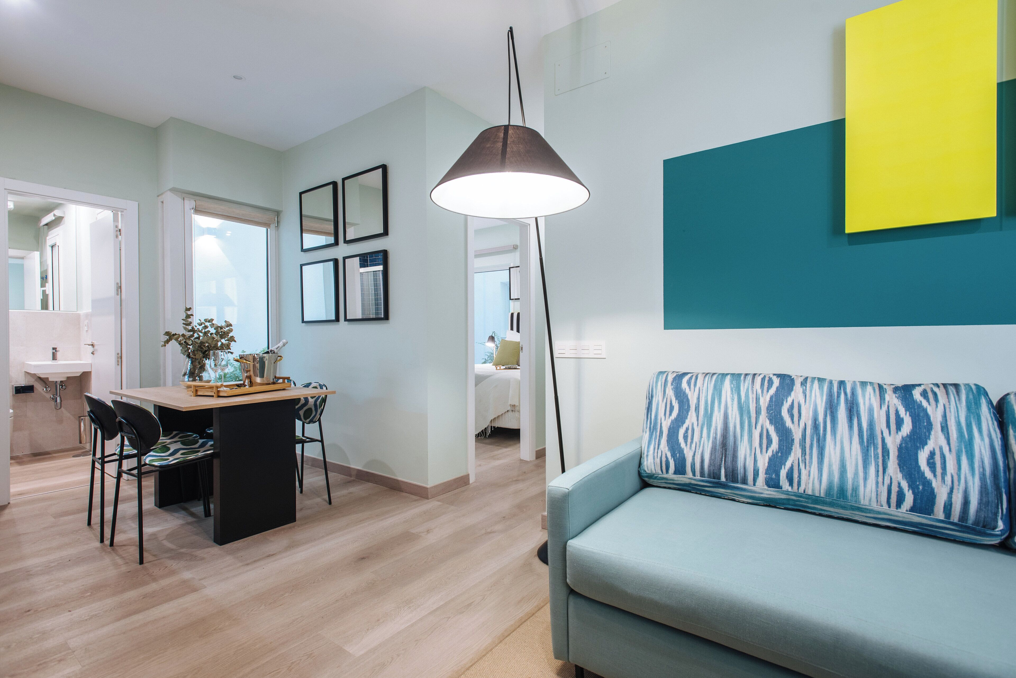 A modern living room with a sofa, a dining table with chairs, and a pendant light.