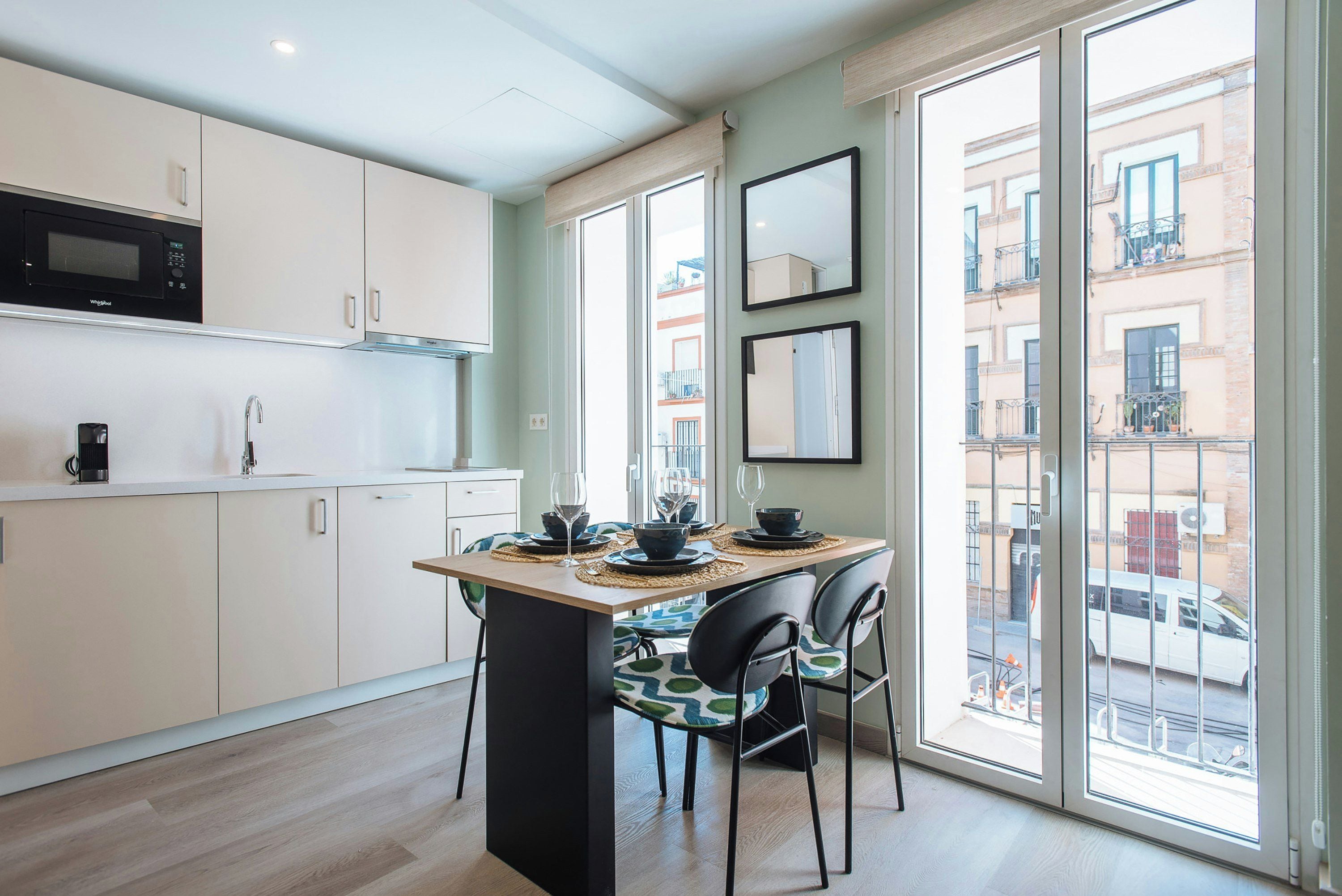 Una cocina moderna con microondas, armarios y comedor con sillas y una mesa para dos.