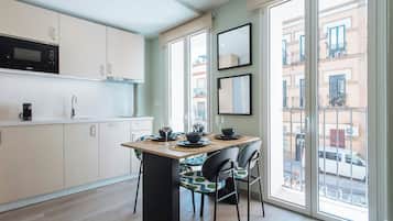 Una cocina moderna con microondas, armarios y comedor con sillas y una mesa para dos.