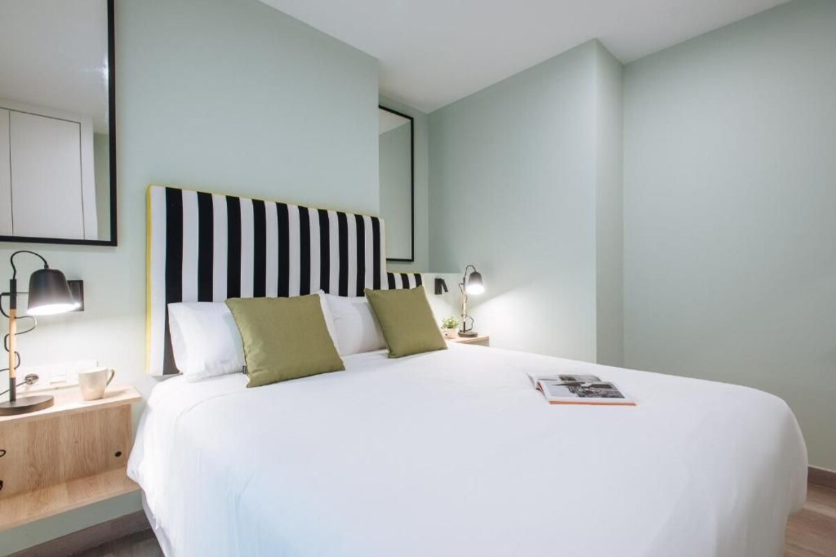 Quarto moderno com uma cama grande, mesas de cabeceira e cabeceira listrada.