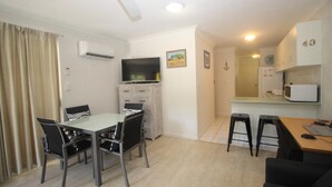 Un espacio habitable compacto con comedor, kitchenette y un pequeño bar.