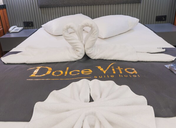 Uma cama com o logotipo do hotel Dolce Vita suite, um telefone e uma mesinha de cabeceira.