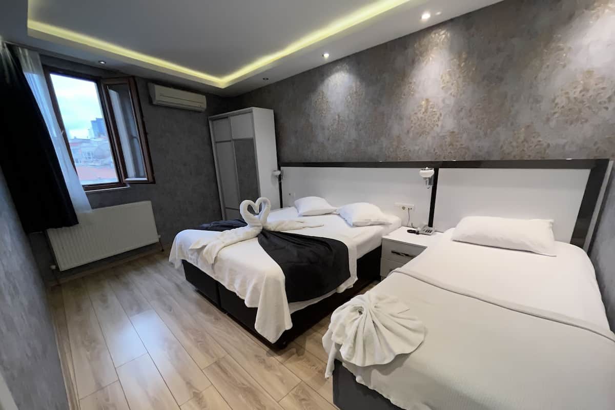 A modern hotel room with two beds, a wardrobe, a radiator, and a window with a view.